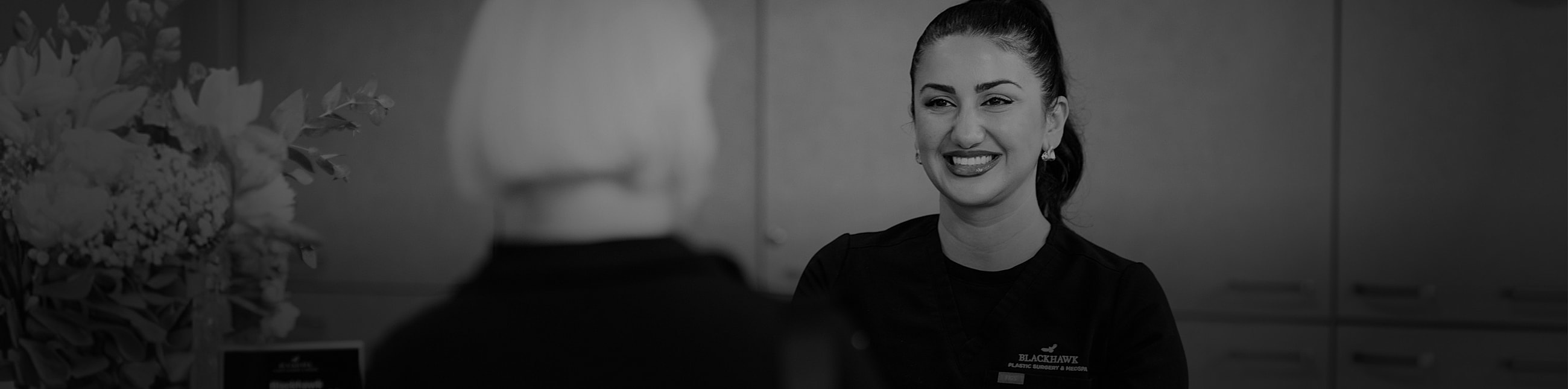 Smiling professional with flowers in background.