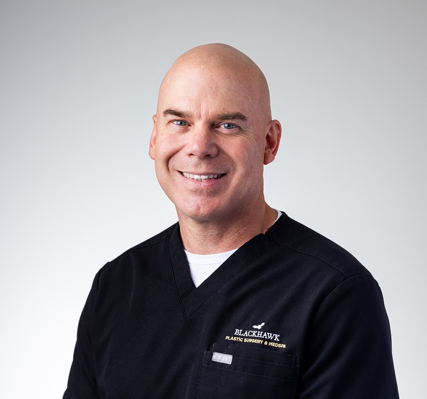 Bald man smiling in medical attire.