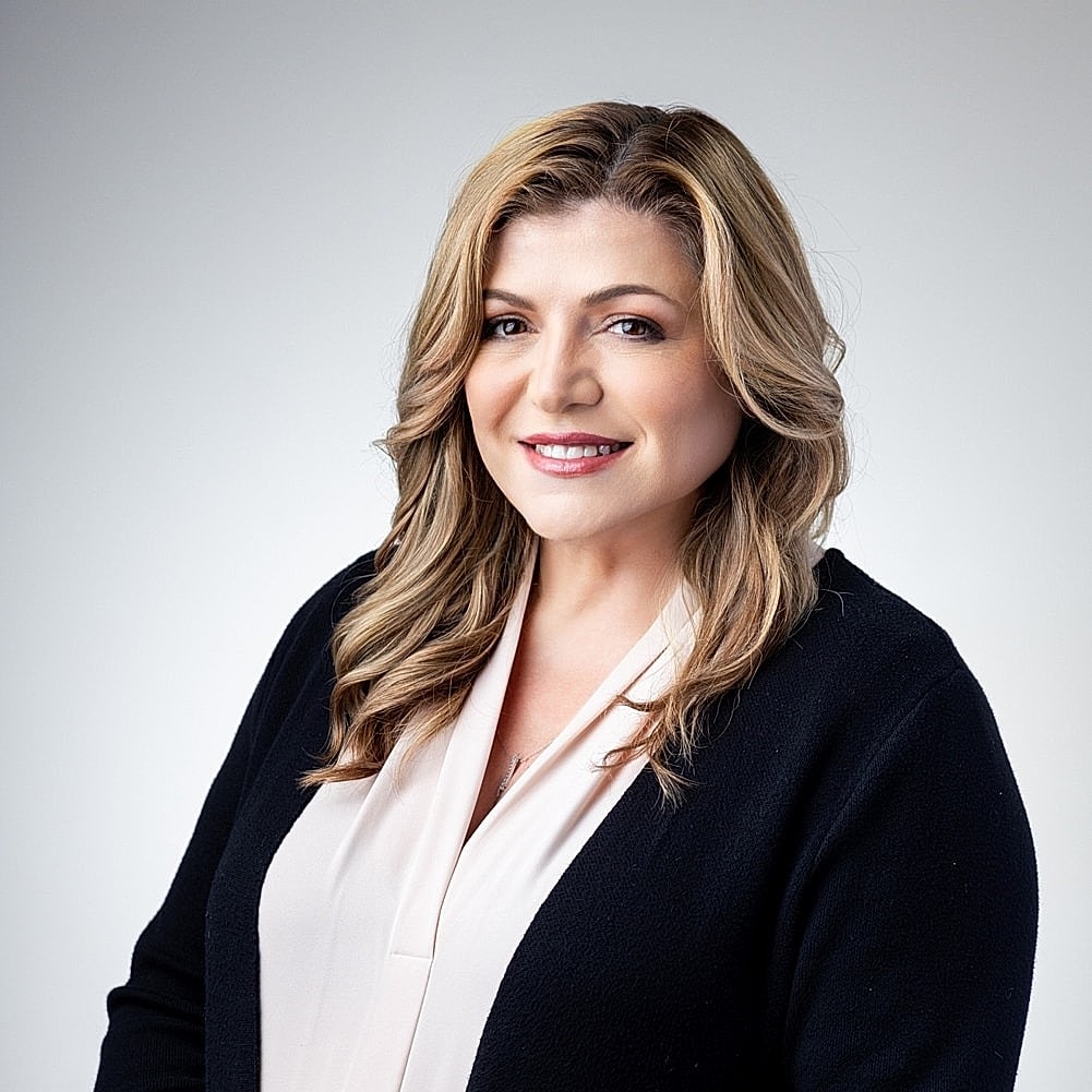 Woman in professional attire, smiling confidently.