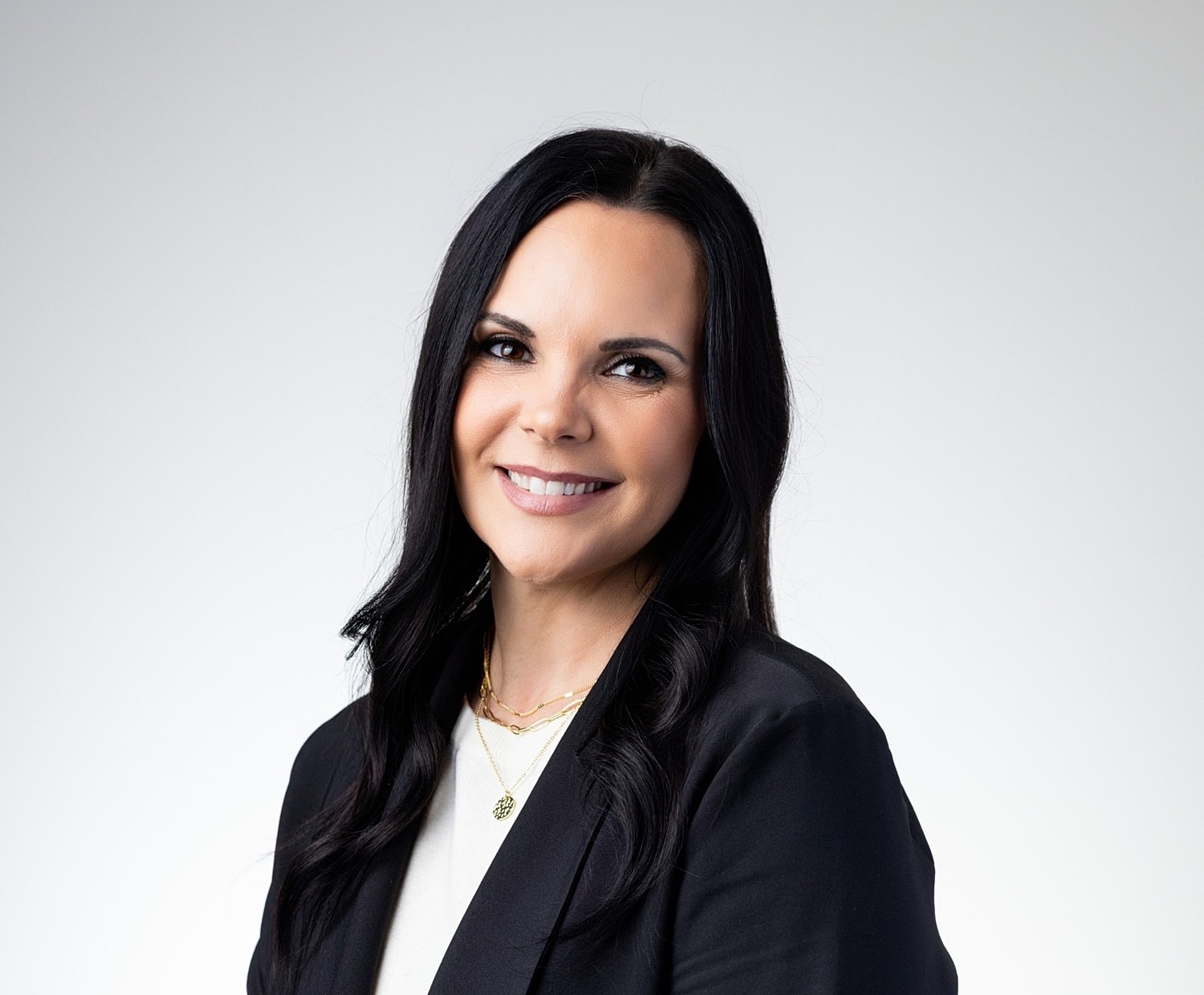 Smiling woman in professional attire against plain background.