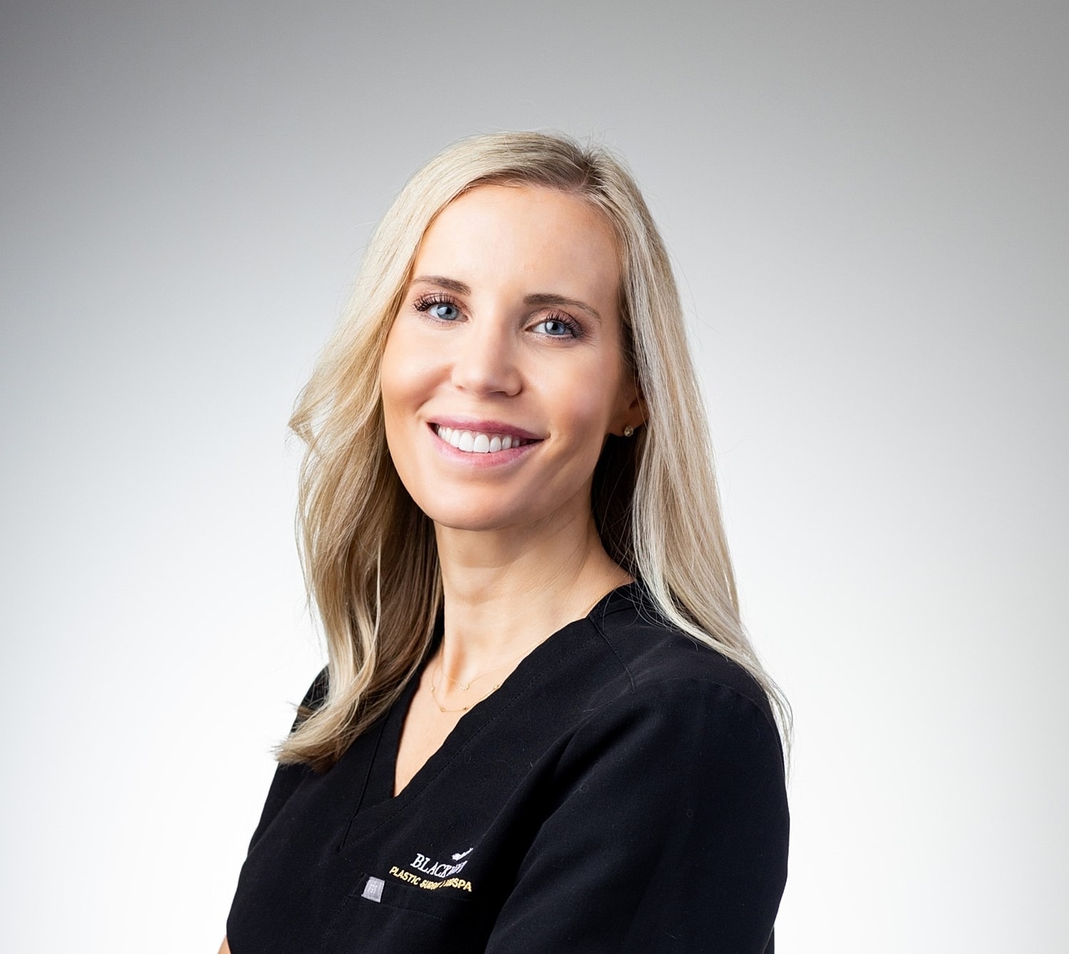 Smiling professional in medical attire with light background.