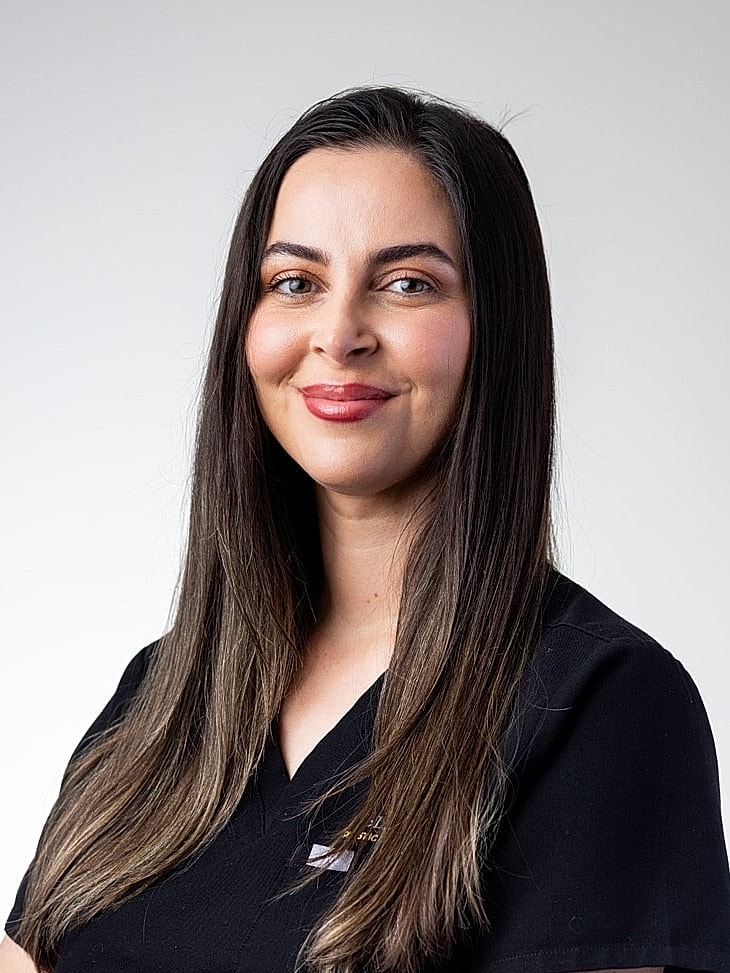 Smiling professional in medical attire with crossed arms.