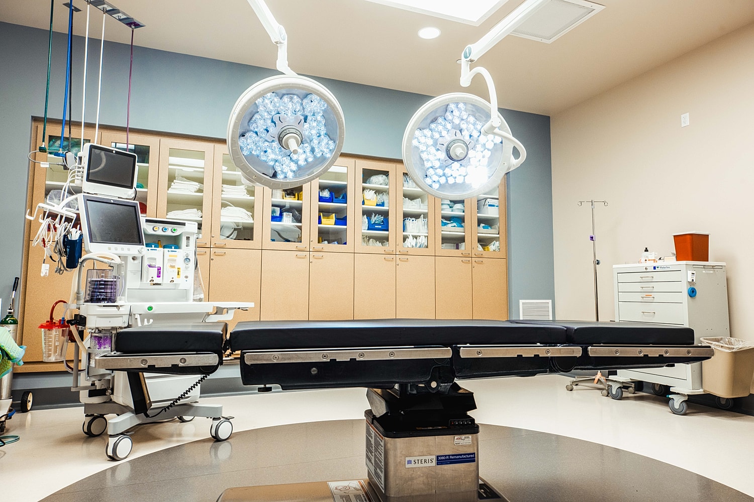 Modern operating room with surgical equipment and lights.