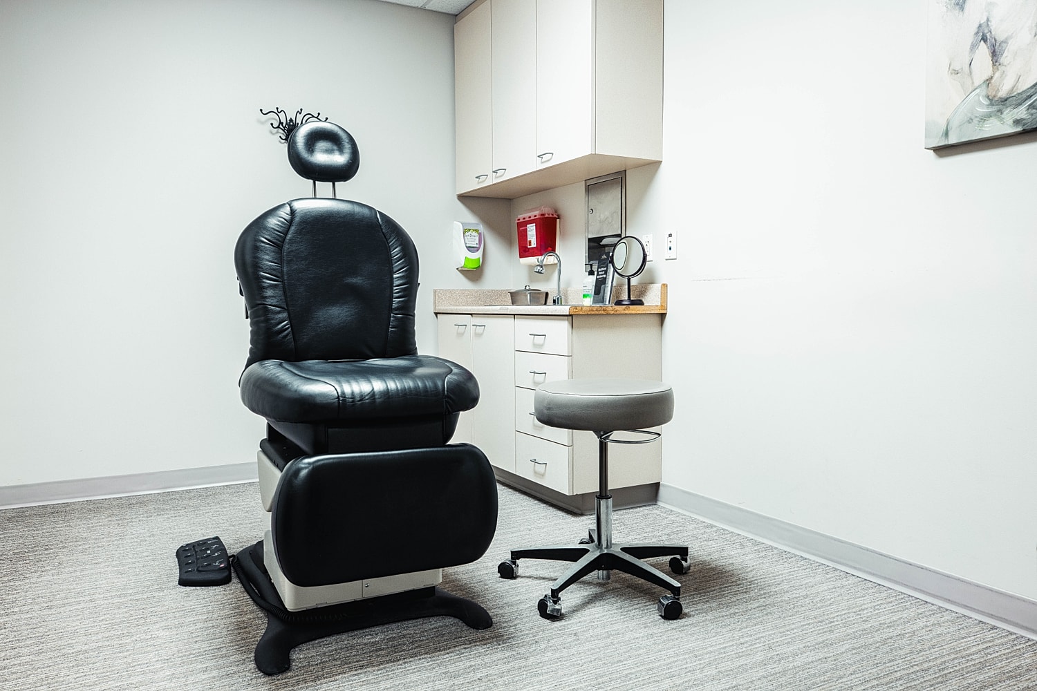 Empty medical examination room with black chair.
