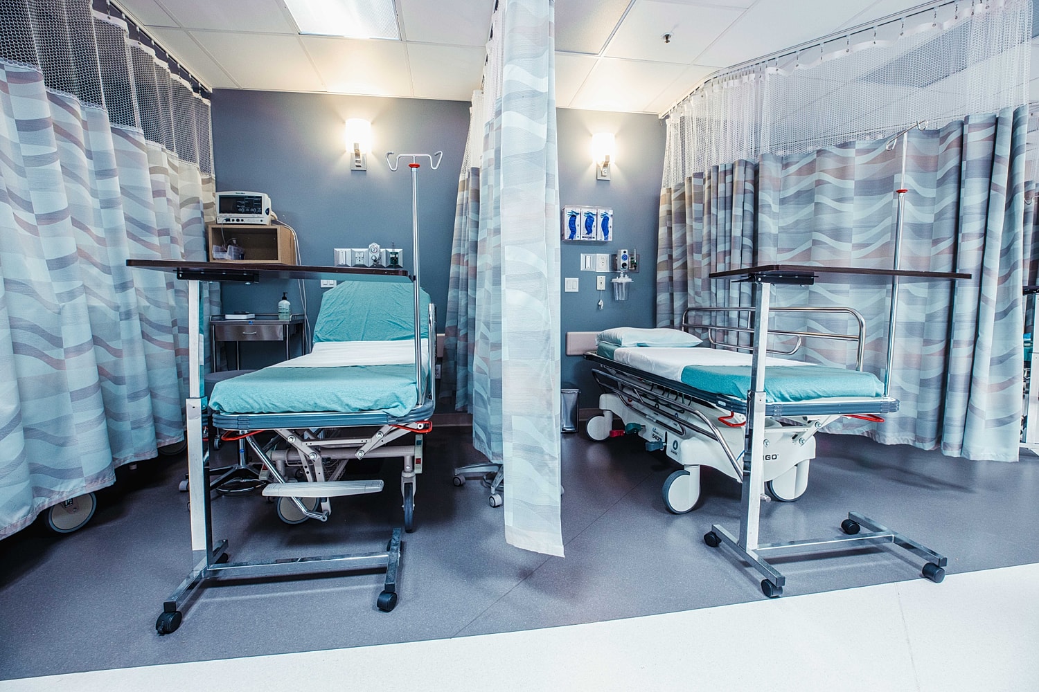 Hospital room with medical beds and curtains.
