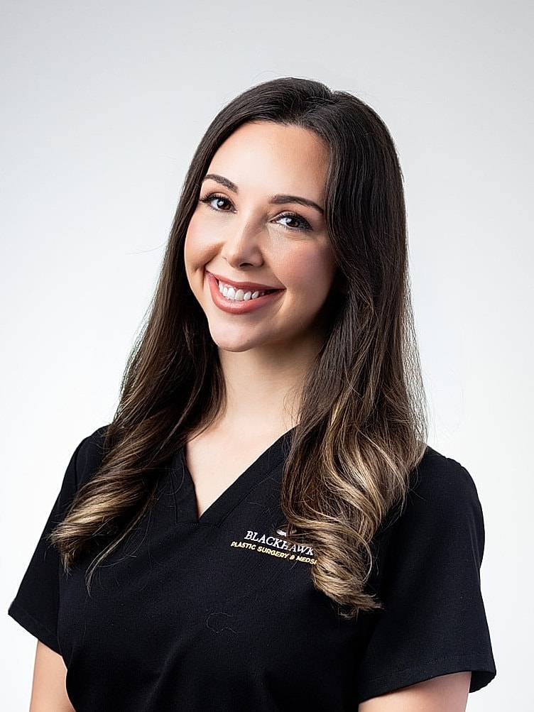 Smiling woman in medical attire, professional setting.