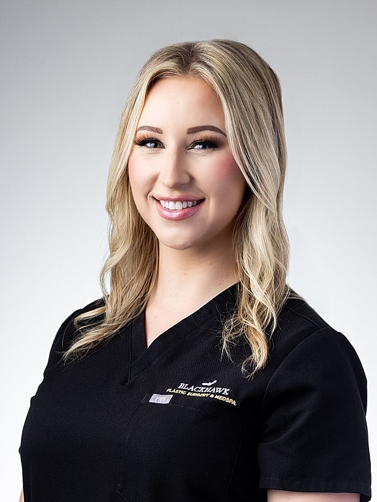 Smiling professional in medical attire against neutral background