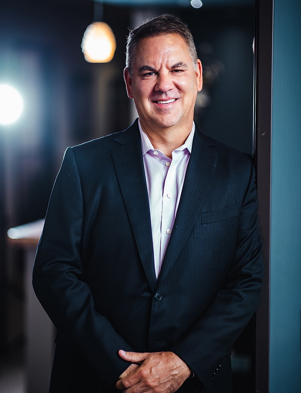 Man in suit smiling indoors.