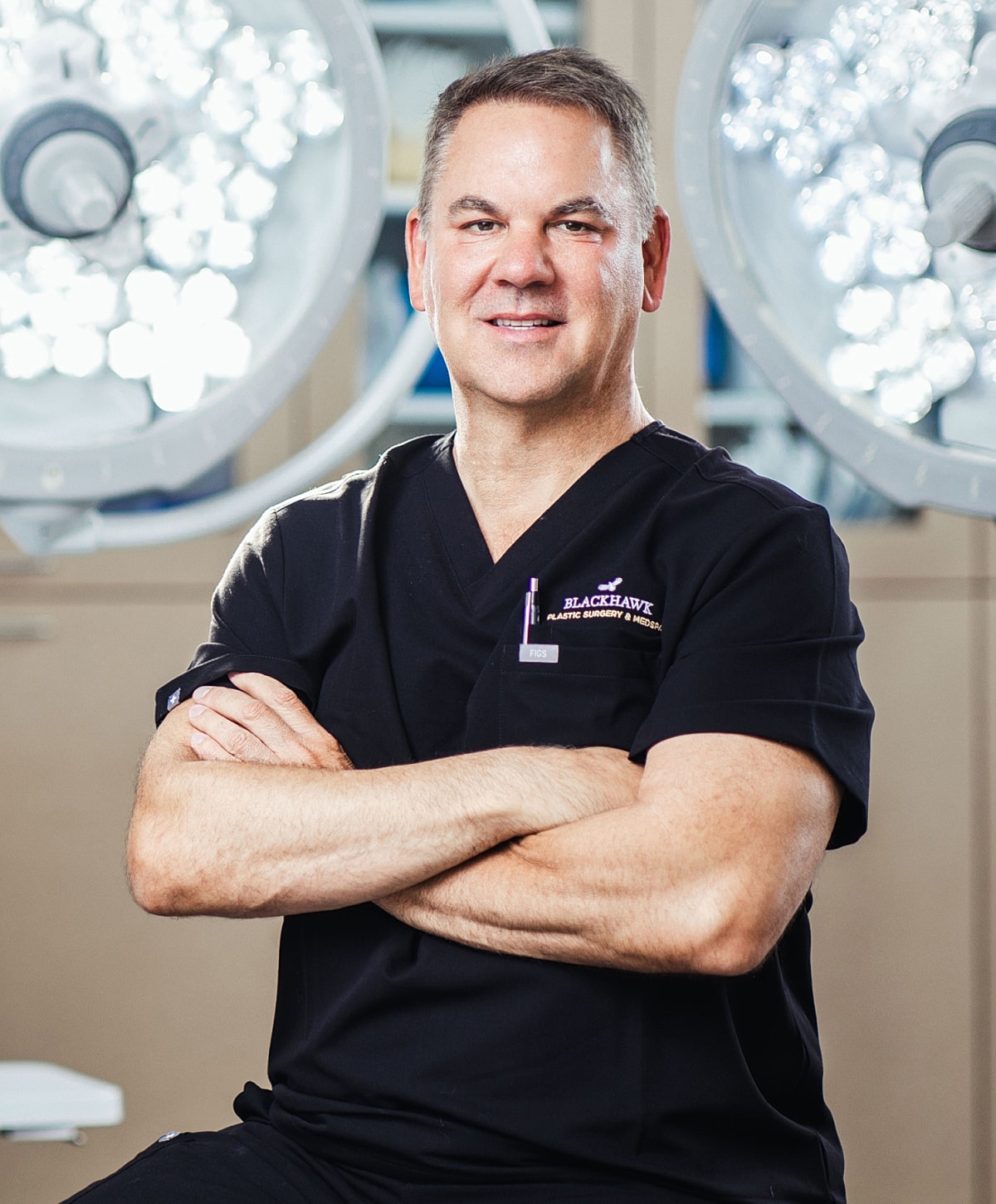 Smiling male surgeon in operating room attire.
