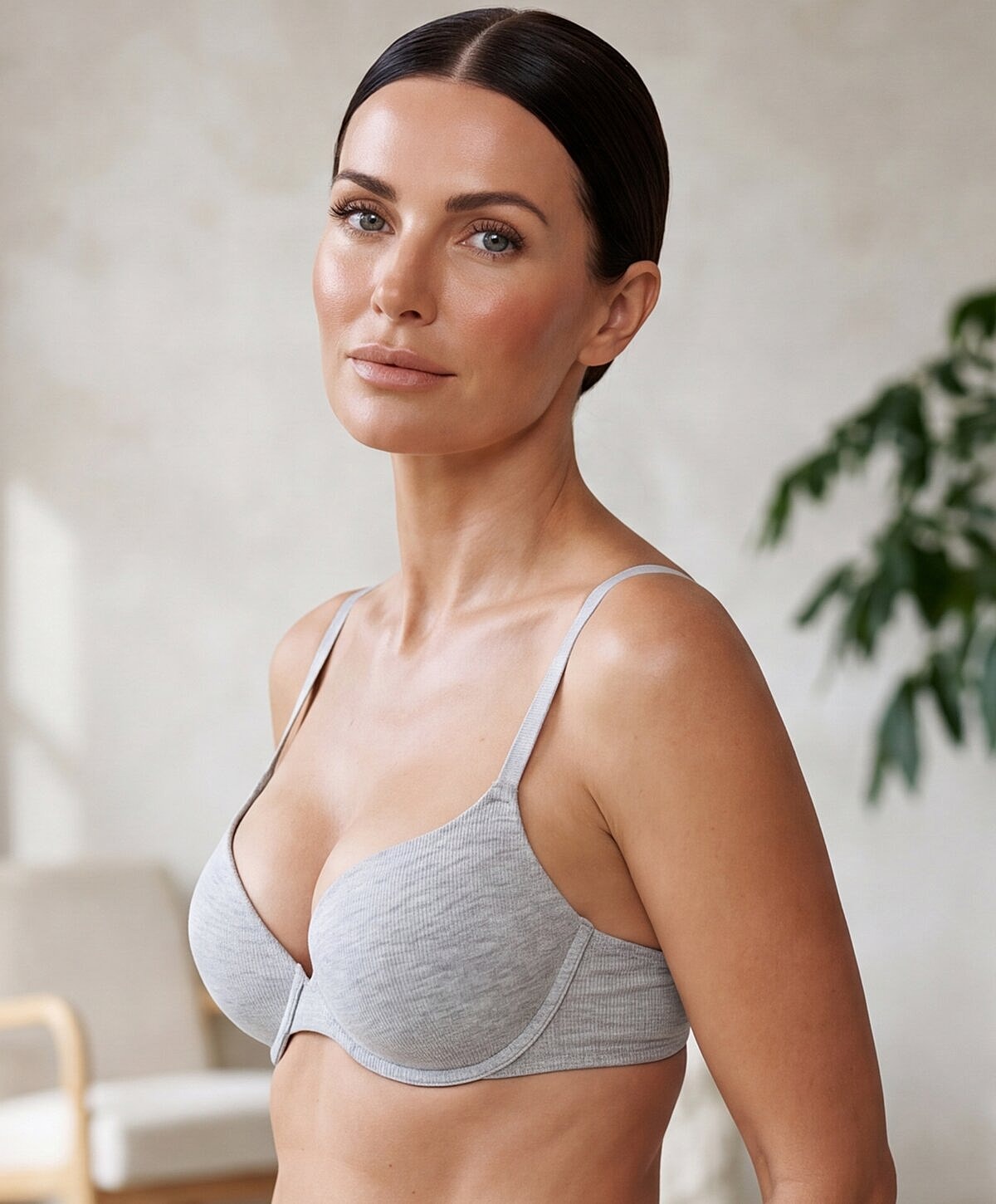 Woman modeling a gray bra in soft lighting.
