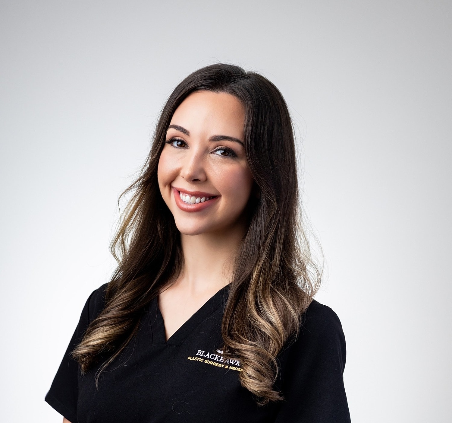 Smiling professional in medical uniform against white background.