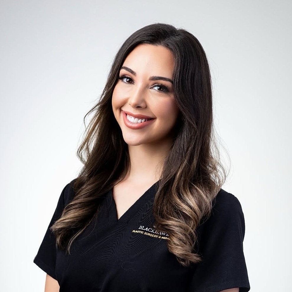 Smiling woman in black medical scrubs.