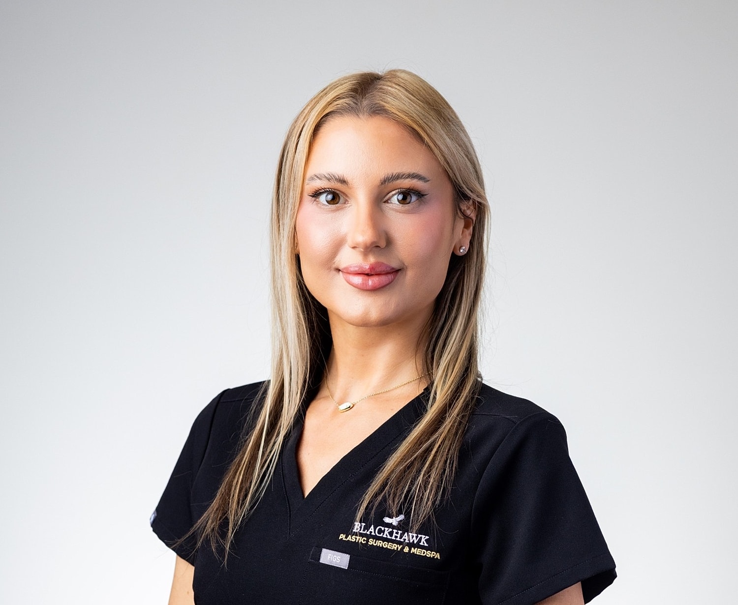 Medical professional in scrubs, smiling confidently.