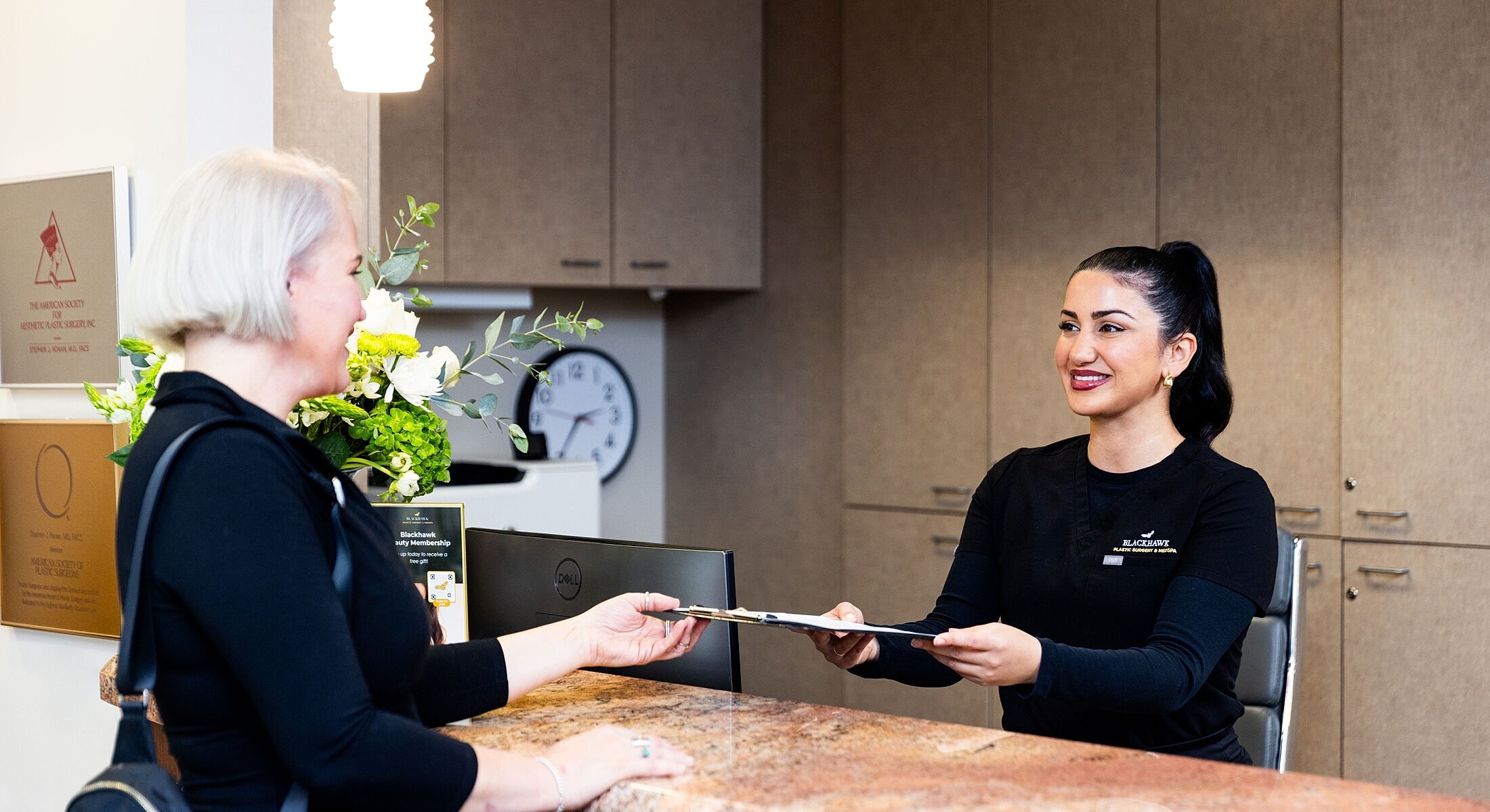 Receptionist assisting a client at a desk.