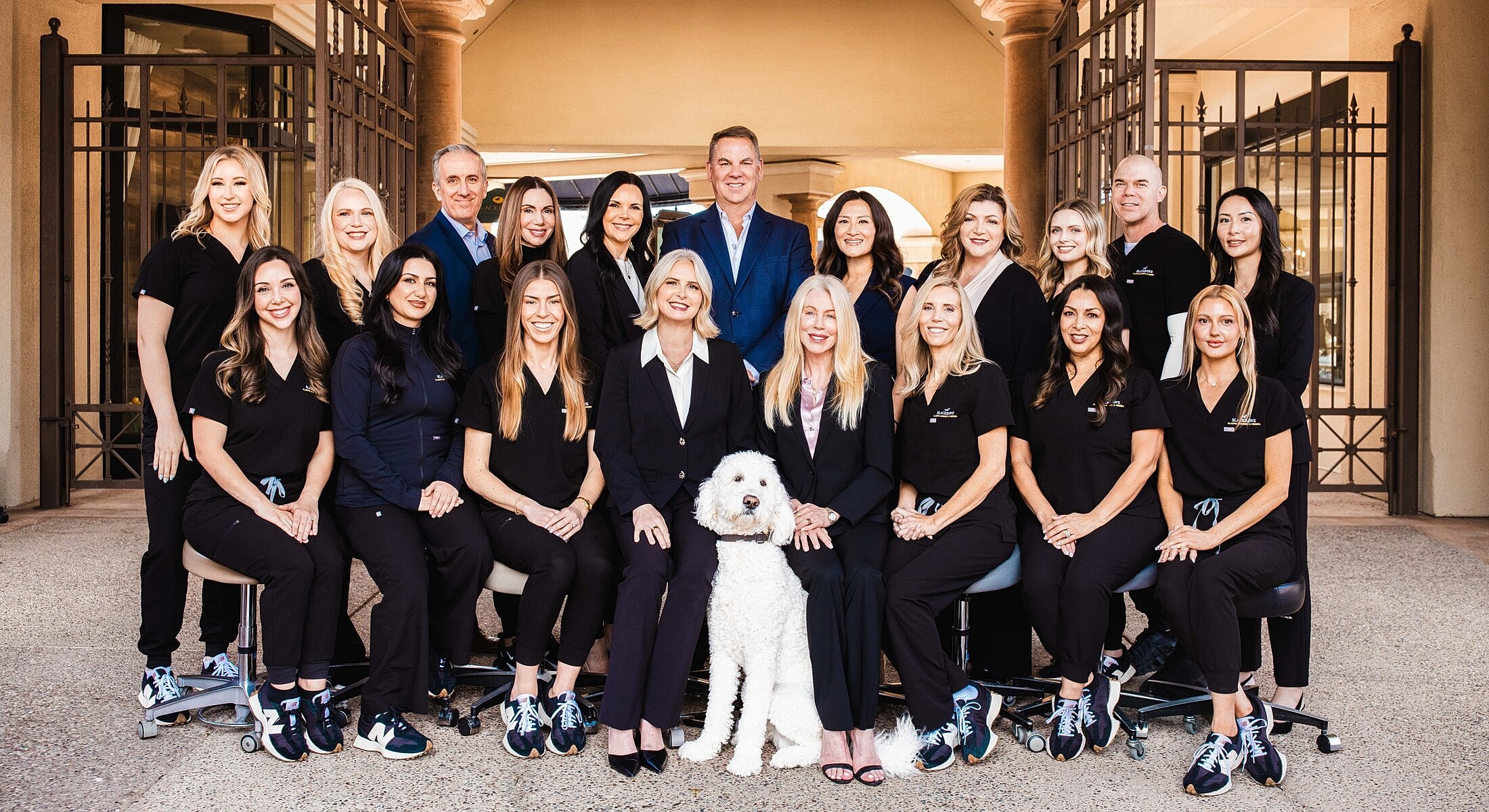 Dental team posing with a dog outdoors.