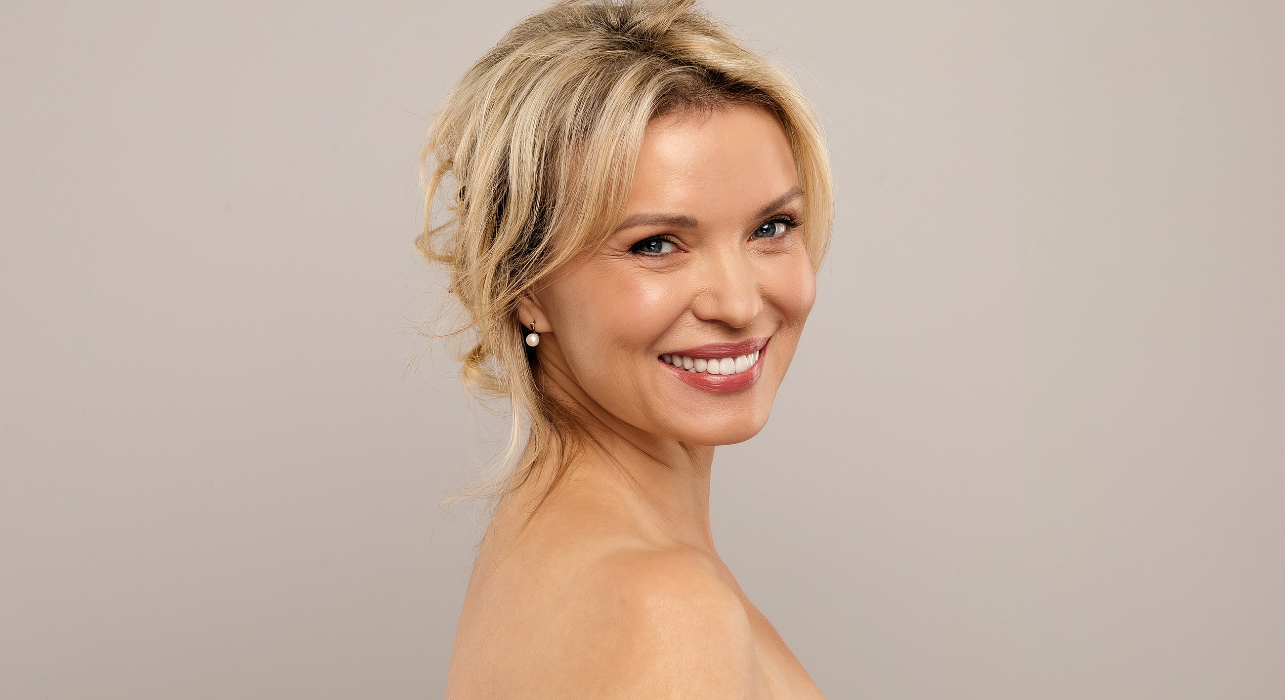 Smiling woman with blonde hair and earrings.