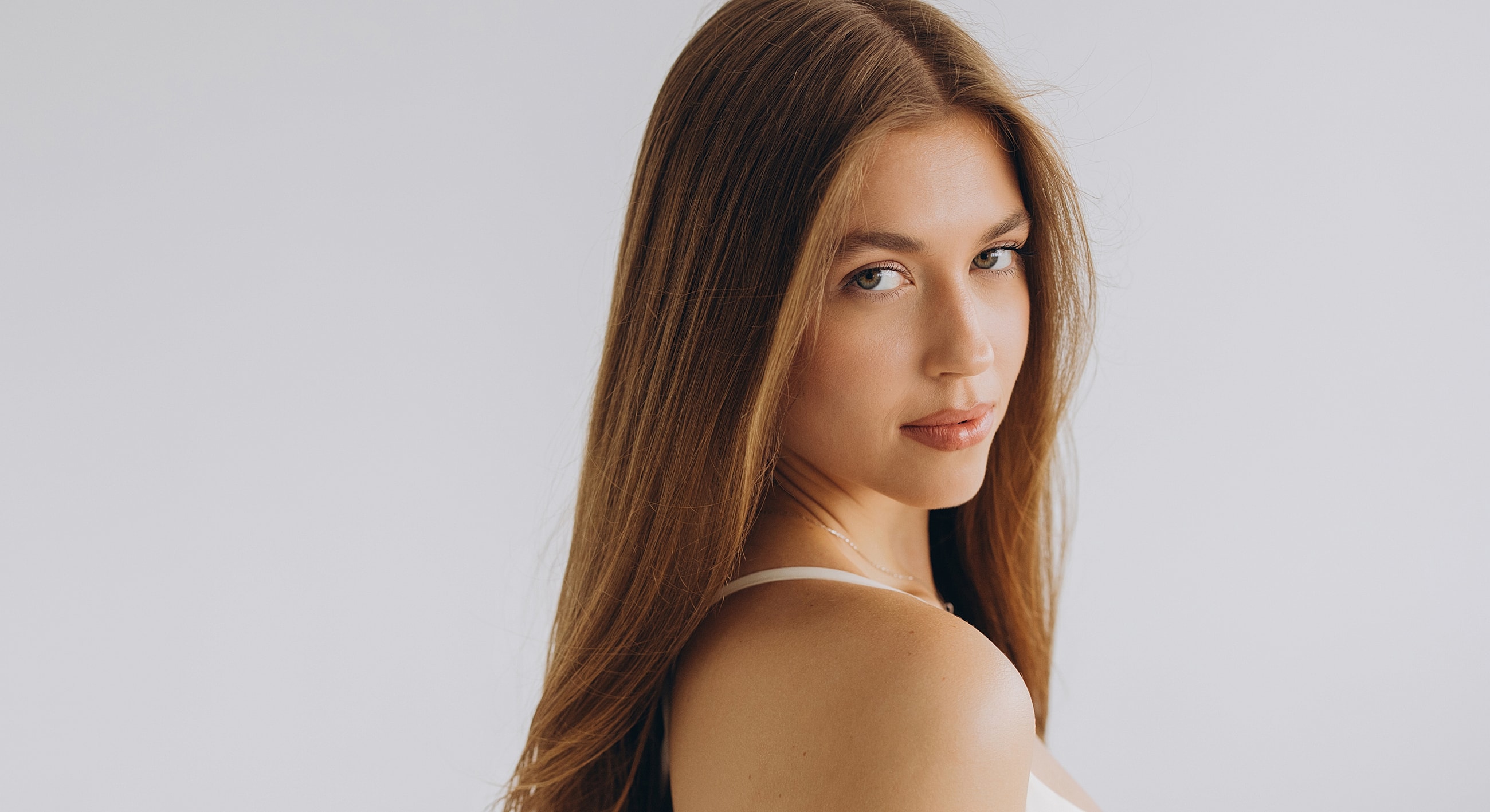 Young woman with long hair looking back.