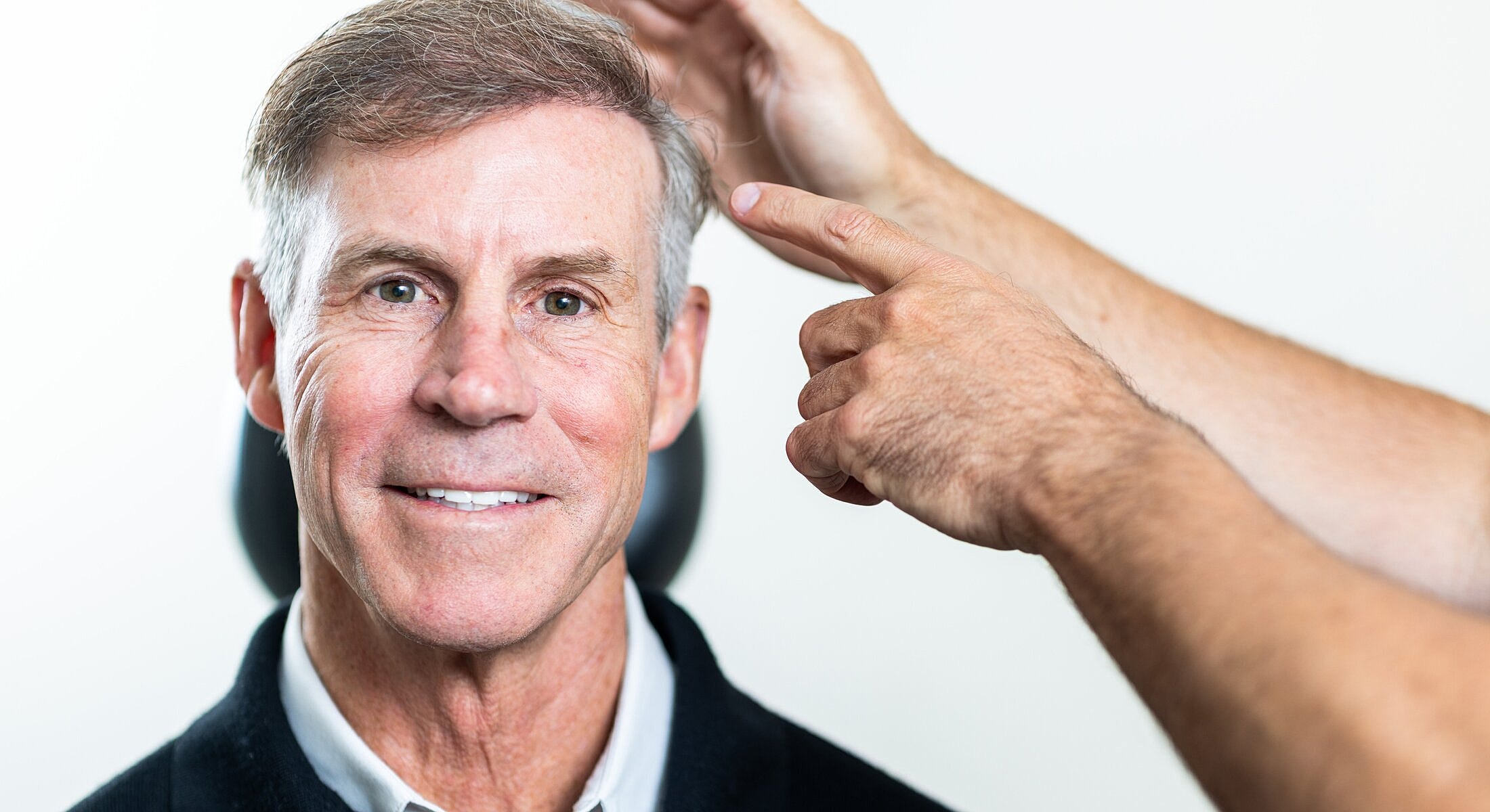 Man smiling while receiving a hair consultation.