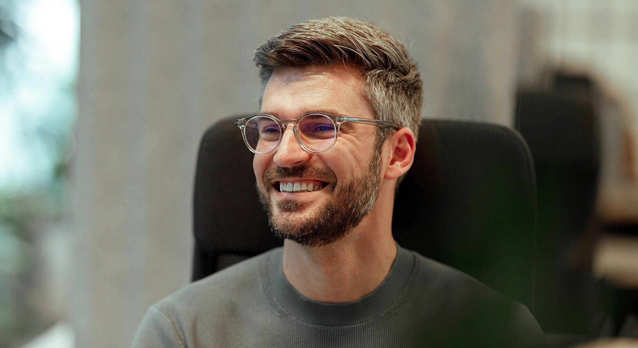 Smiling man in glasses in modern workspace.
