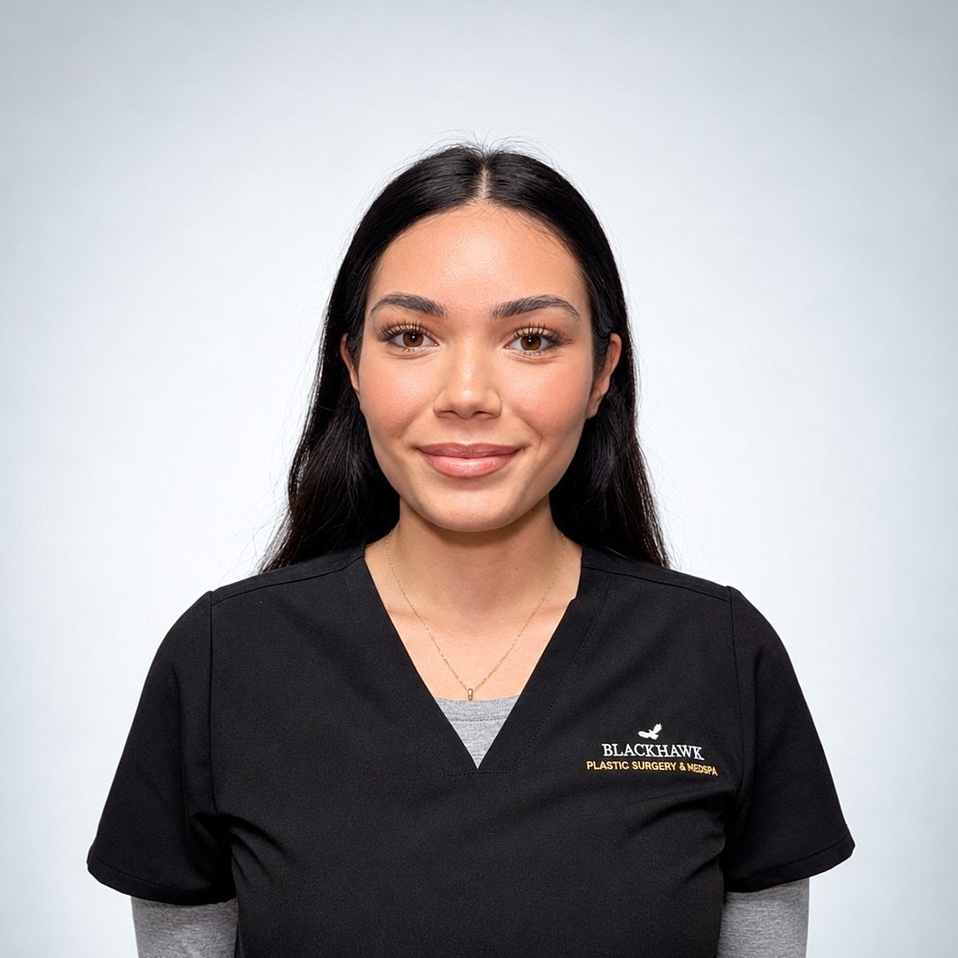 Female medical professional in scrubs, smiling.