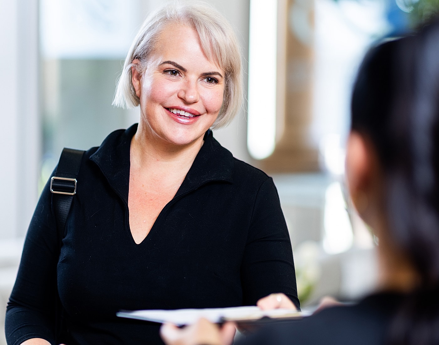 Smiling woman interacting in a bright setting.