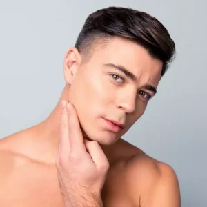 Male patient with clean complexion touching face, representing skincare results